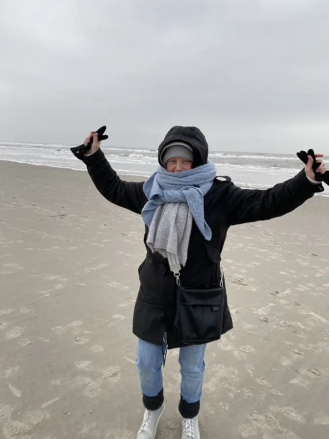 Constanze steht im Dezember auf dem Strand von St. Peter Ording, warm angezogen mit 2 Schals